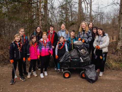 Slovenian Scouts smile holding trash bags.