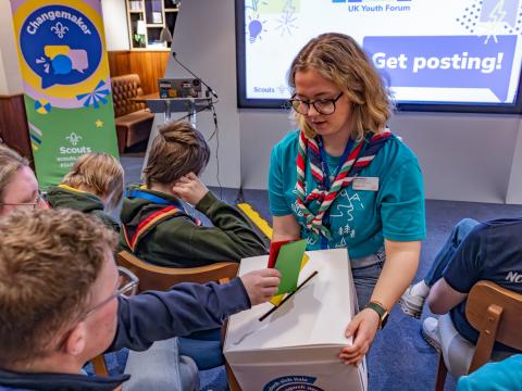 Scouts post their ballots inside a voting-urn.