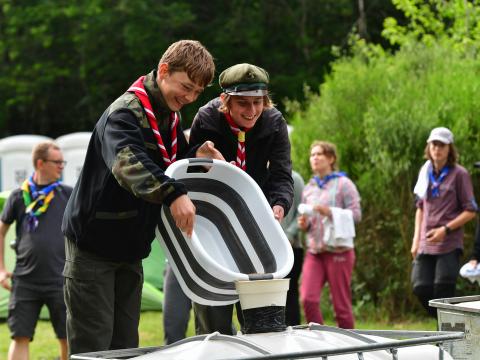 Two Polish Scouts pour a bucket into another container