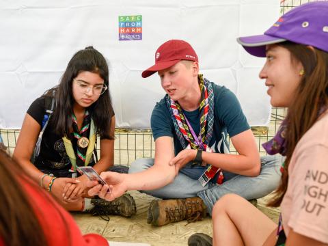 3 Scouts assis discutent d'À l'abri de la maltraitance lors du Jamboree Scout Mondial en Virginie Occidentale