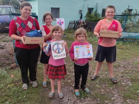 Una familia ucraniana de cuatro sostiene una caja de zapatos que acaban de recibir de scouts españoles.