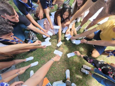 Un groupe de jeunes Scouts forme un cercle et montre des morceaux de papier.