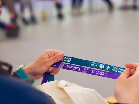 A participant holds two ribbons from Scouts and Dialogue for Peace.