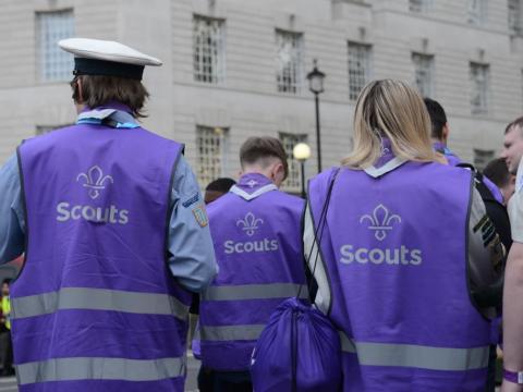 Trois Scouts portant des vestes de haute visibilité violettes avec la fleur de lis scoute.