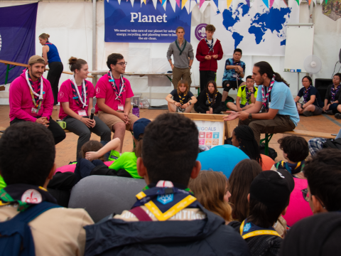 A group of young people wearing scarves talk in front of others.