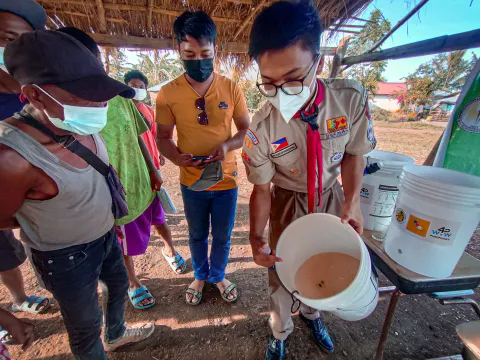 Raymund Romeo Guzman showing a bucket full of dirty water