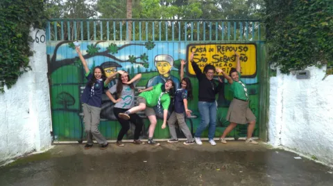 Scouts in Sao Paolo of União dos Escoteiros do Brasil pose in front of a colourful gate while working on a project to help the environment and easing poverty