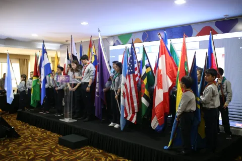 Interamerican Scouts gather on stage with flags from their respective countries