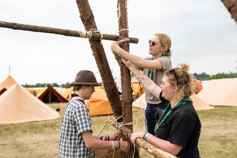 3 Scouts at the Denmark National Jamboree work together to assemble a pioneering project