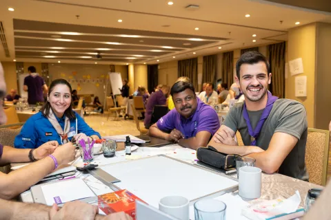 Three adult Scout volunteers sit at a table laughing during a workshop